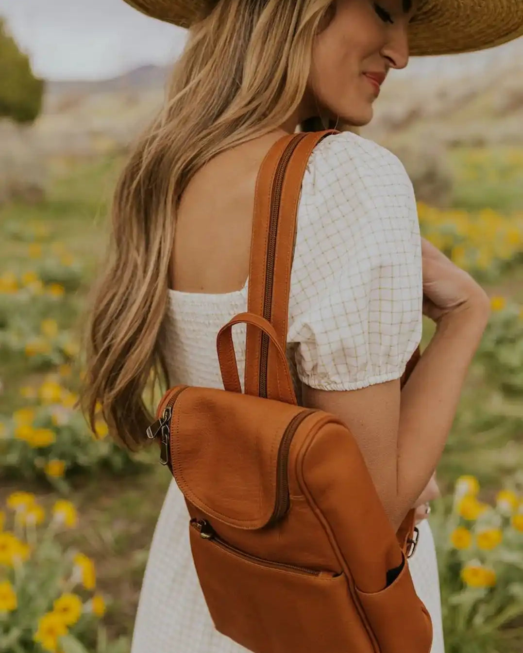 Un sac à dos en cuir marron clair d'une femme porté sur une épaule.