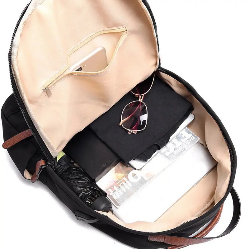 Sac à dos ouvert noir avec accents marron contenant des affaires personnelles pour garçon d’école classique