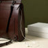 Sac à messenger en cuir vintage marron profond avec écouteurs blancs à proximité