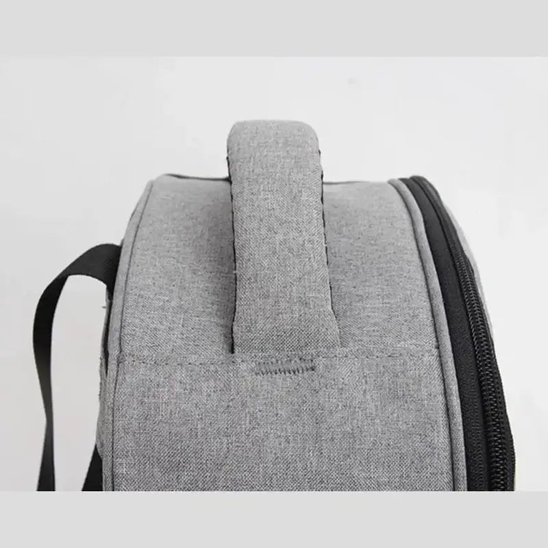 Gros plan d’un sac à dos isotherme gris avec poignée supérieure et fermeture éclair noire