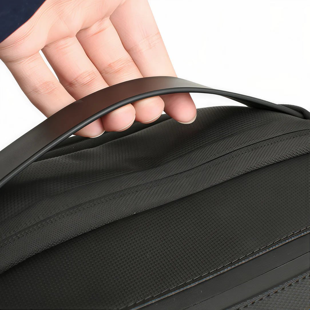 Main d’une personne tenant la sangle noire du sac à dos gris texturé SafePort