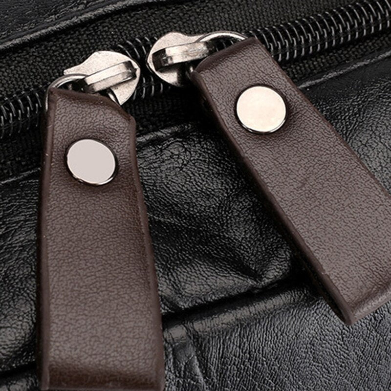 Deux tirettes en cuir marron avec snaps argentés sur un sac à dos en cuir noir pour homme