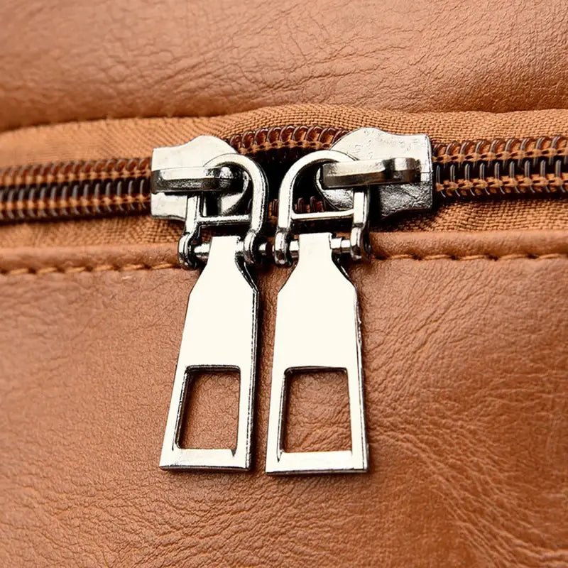 Deux tirettes de fermeture éclair argentées sur un sac à dos en cuir souple pour femme