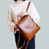 Femme en pull blanc et pantalon foncé tenant un sac à dos en similicuir brillant