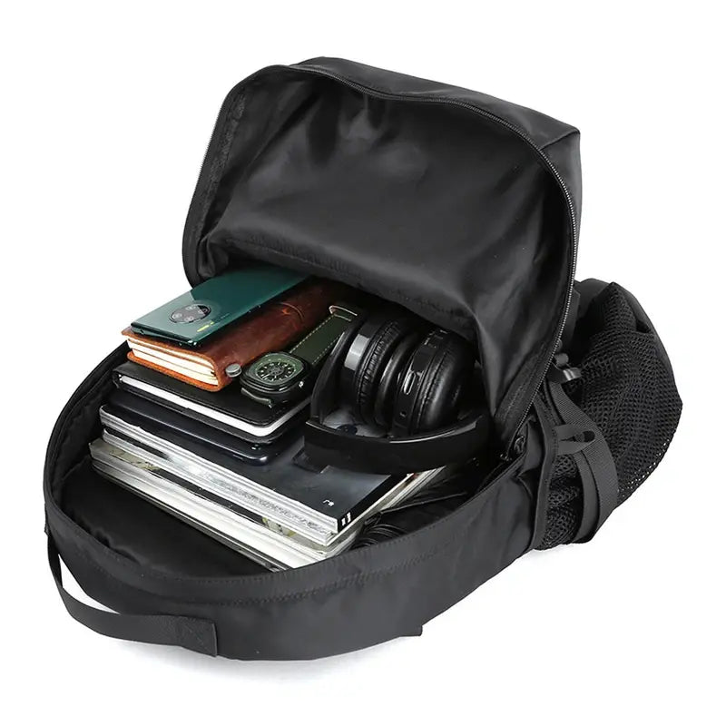 Sac à dos homme tendance noir ouvert avec divers articles personnels à l’intérieur
