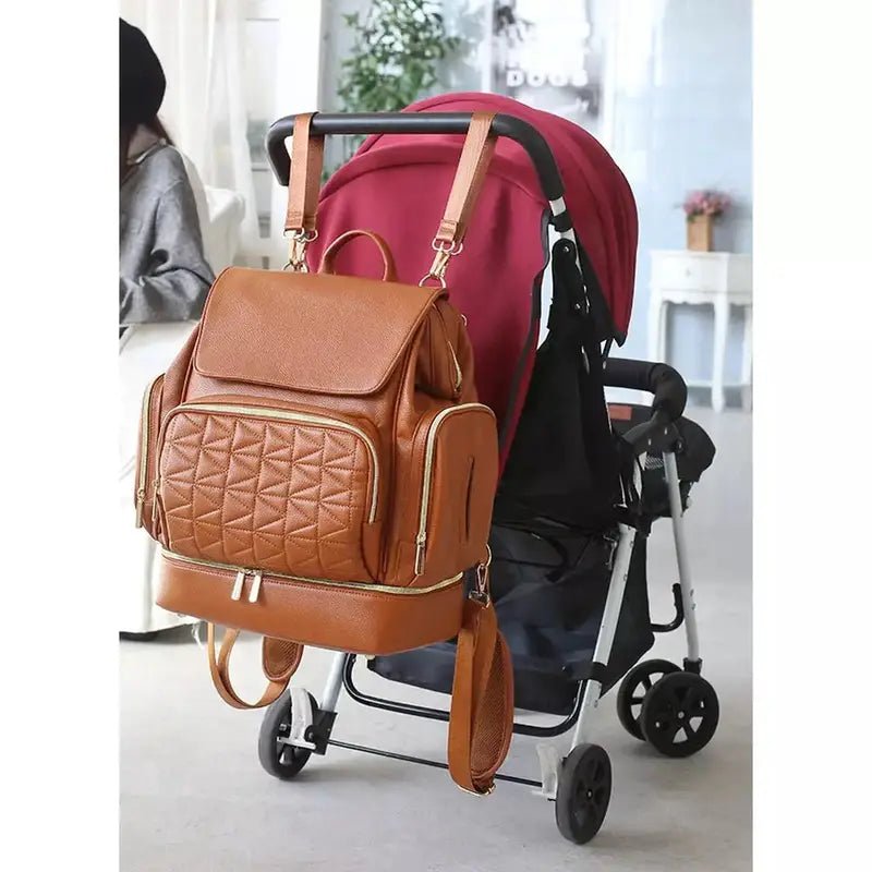 Sac à dos à langer en cuir marron avec poche texturée, suspendu au poussette