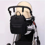 Sac à dos à langer design noir suspendu sur une poussette pour bébé