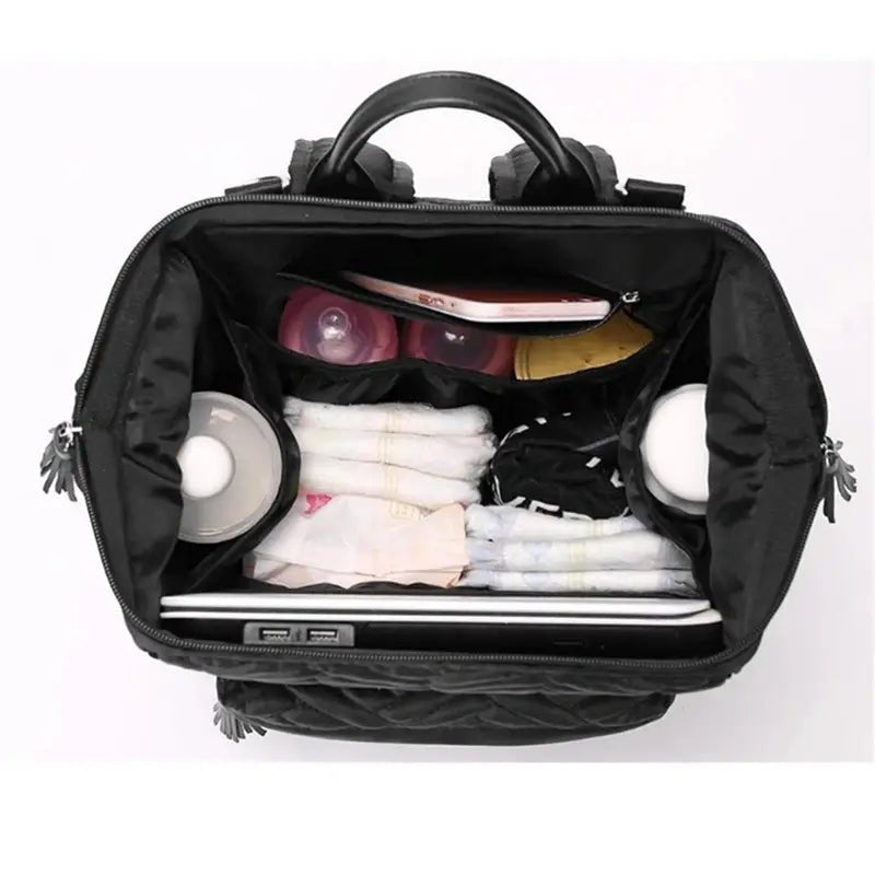 Sac à dos à langer design noir ouvert avec essentiels pour bébé et ordinateur portable
