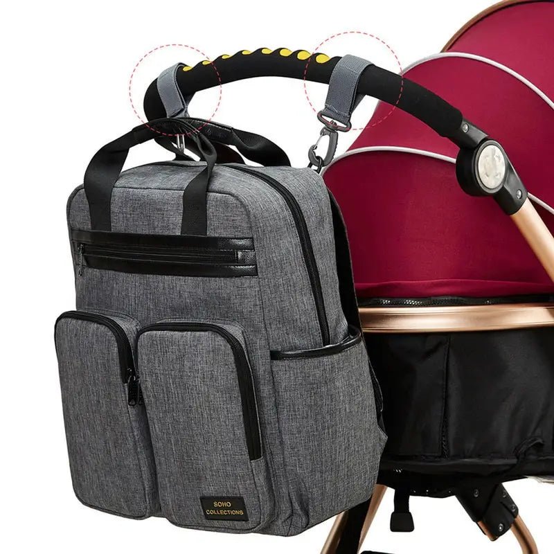 Sac à dos à langer gris avec plusieurs poches suspendu au guidon de la poussette