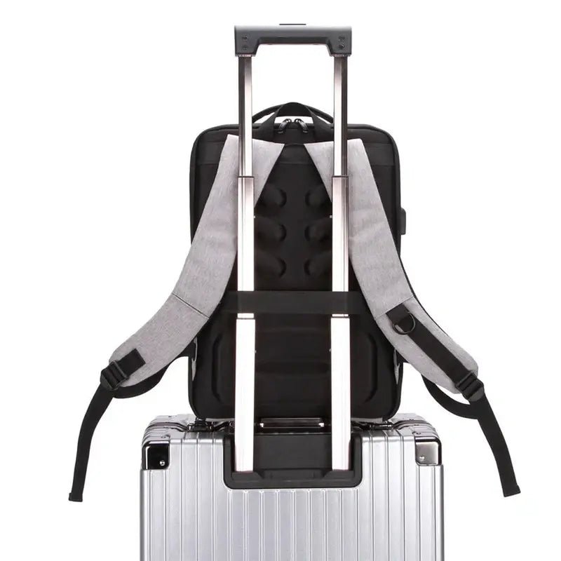 Sac à dos ordinateur 15 pouces antivol noir avec bretelles grises sur une valise argentée