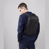 Sac à dos ordinateur portable plat et étanche noir, compact et élégant sur une personne en costume Navy