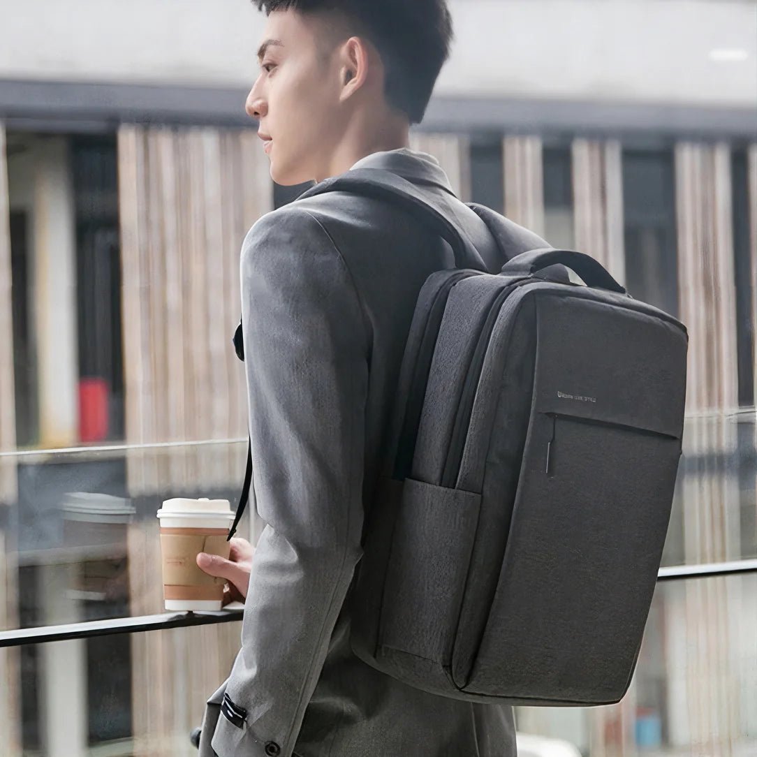 Personne tenant une tasse de café avec un sac à dos gris foncé pour ordinateur portable 17 pouces Urban Nova