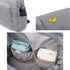 Sac à langer à dos en tissu gris avec compartiments, contenant un parapluie et autres objets